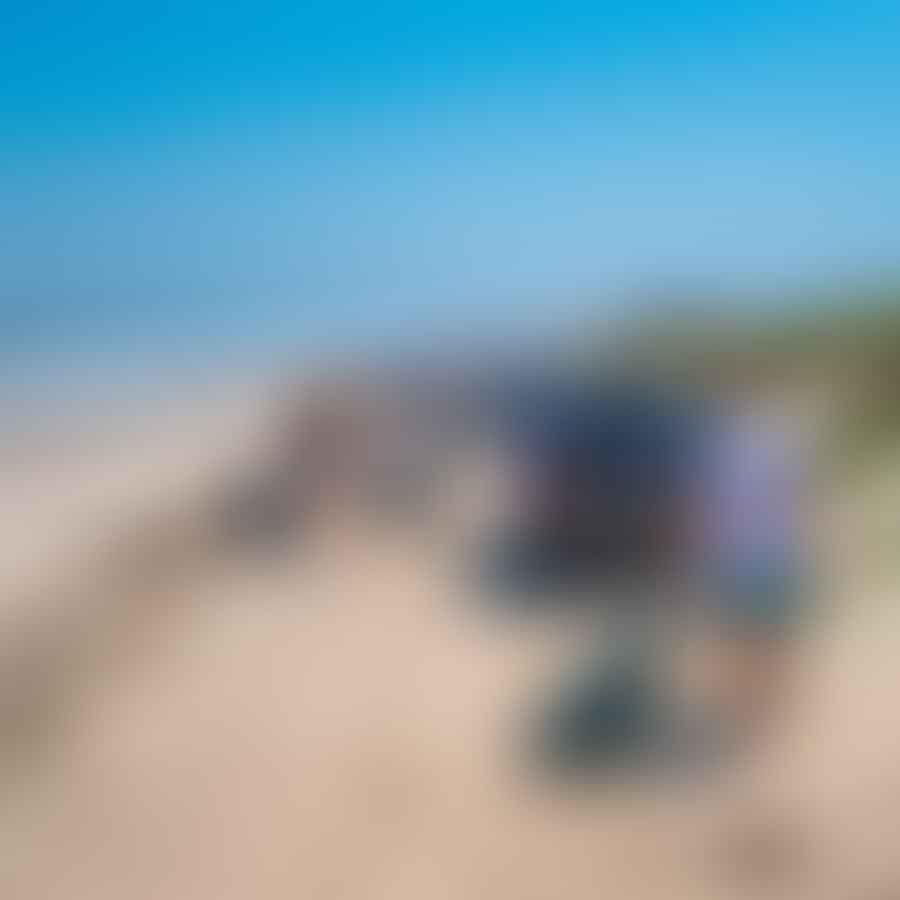 A group of people driving safely on the beach, following designated paths, and maintaining a respectful distance from wildlife. They are checking the tides, adhering to speed limits, and carrying necessary equipment like a tow rope, tire pressure gauge, and shovel. In the background, a clean beach with no trash can be seen, emphasizing the importance of packing out trash and leaving the beach cleaner than it was found.